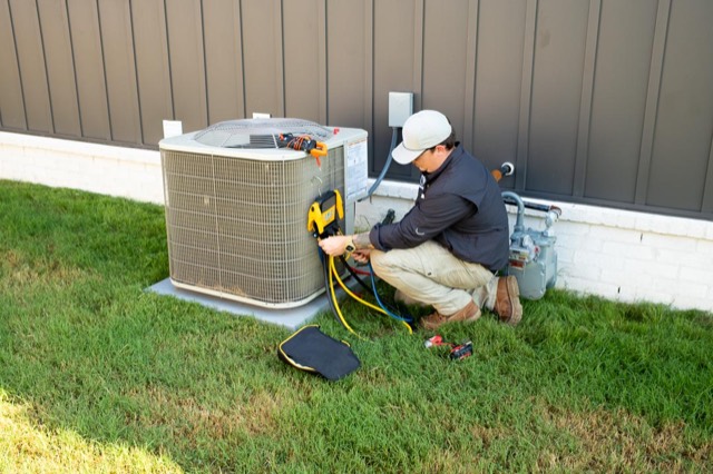 Clark technician servicing an AC condenser beside a Florence home